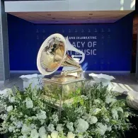 Grammy award display on a floral stage with a blue backdrop reading 