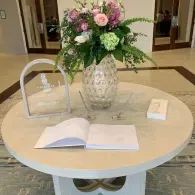 Flower arrangement and guestbook on a round table at an indoor event entrance