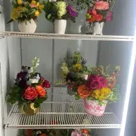 White shelf displaying colorful potted flower arrangements indoors