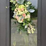 Pastel floral wreath hanging on a glass door with a dark frame