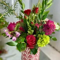 Bouquet of red, pink, and green flowers in a vase on a table