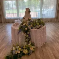 Round table draped in blush cloth with cascading white and yellow floral centerpiece in a bright event hall