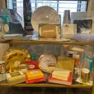Assorted gold and silver tableware, trays, and decorative items displayed on two shelves.
