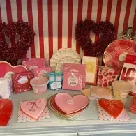 Valentine’s Day display with pink and red heart-shaped gifts, cards, and decorations on striped shelves