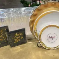 Gold and white ornate plates and black thank-you cards on a decorated table with a gold tablecloth