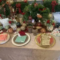 Festive table with holiday desserts and gifts arranged before a Christmas tree backdrop