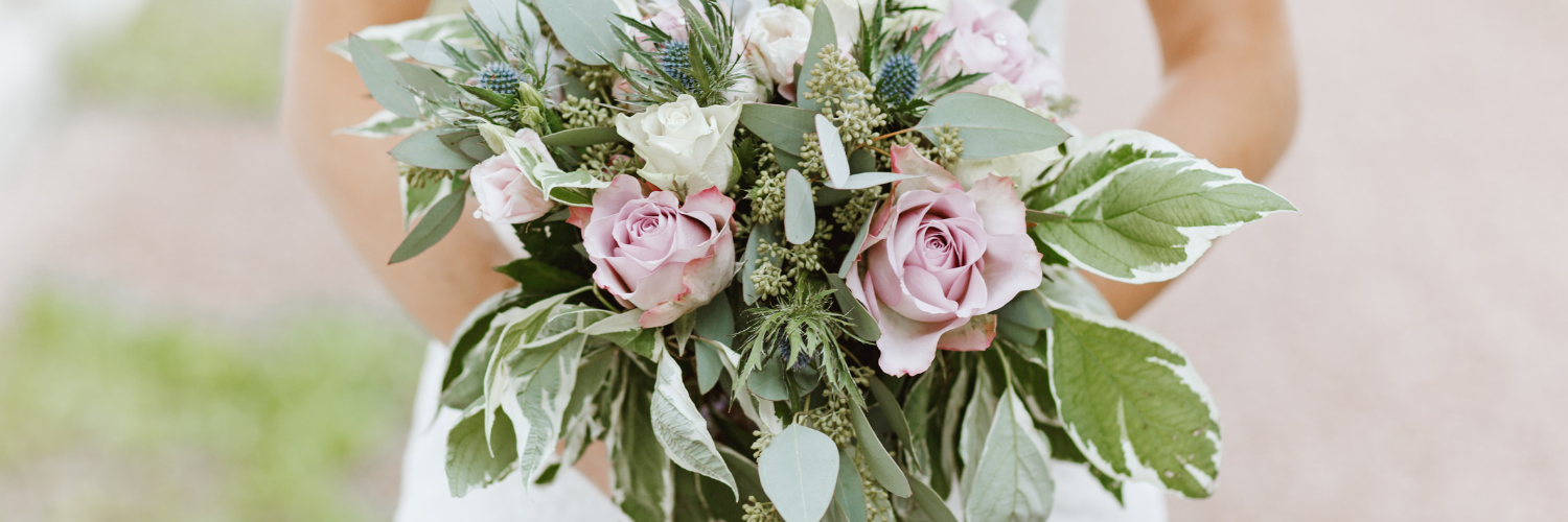 Bouquet of pink roses and white flowers with greenery held in hands