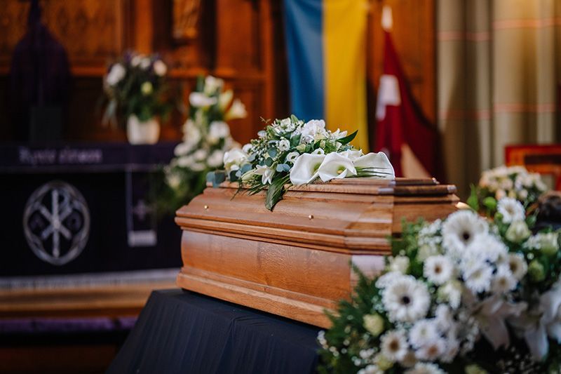 A wooden coffin with flowers on top of it in a church.