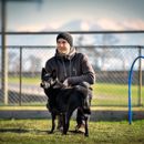 Mann in der Hocke mit seinem schwarzen Hund