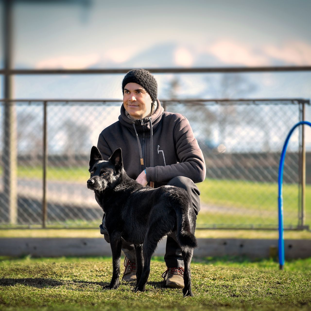 Mann in der Hocke mit seinem schwarzen Hund