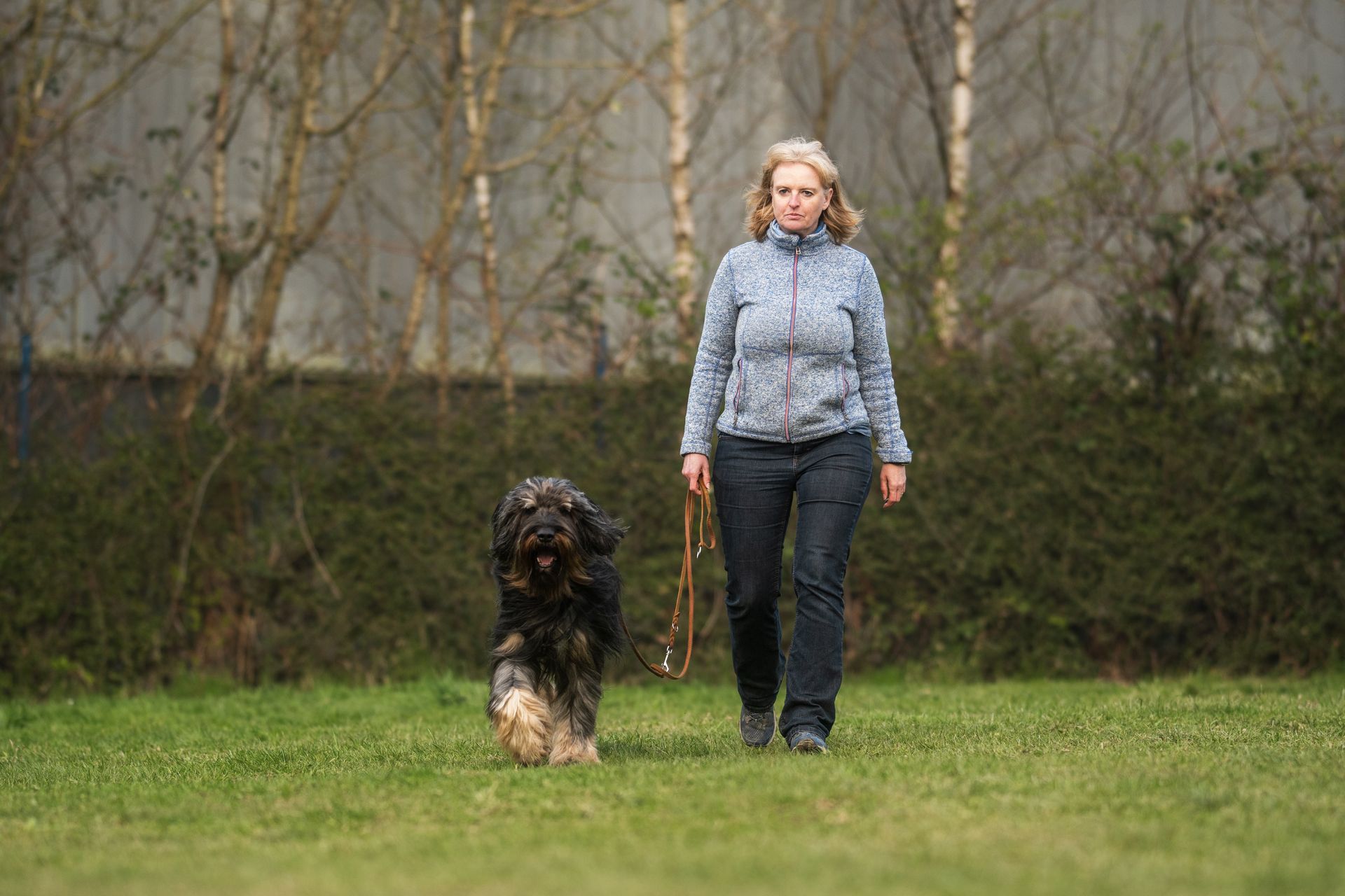 Frau mit Hund in Hoopers Parcours, Hund rennt um eine Tonne herum