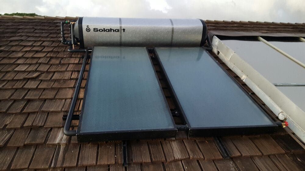 A solar water heater is sitting on top of a wooden roof.