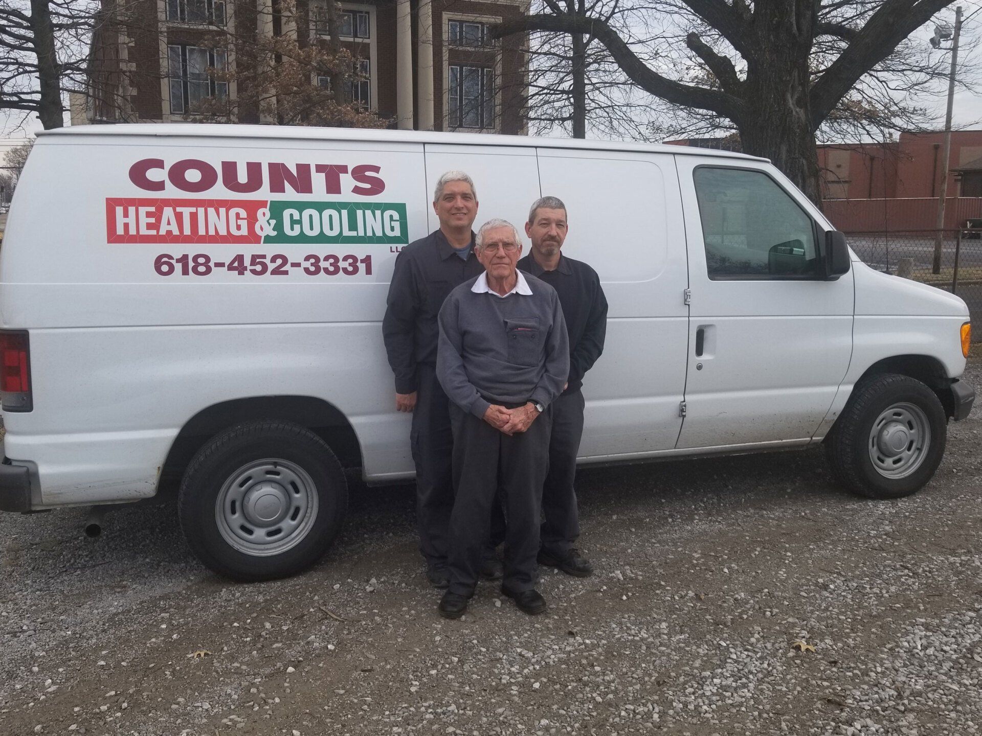 Three people standing in front of a white Counts Heating & Cooling van
