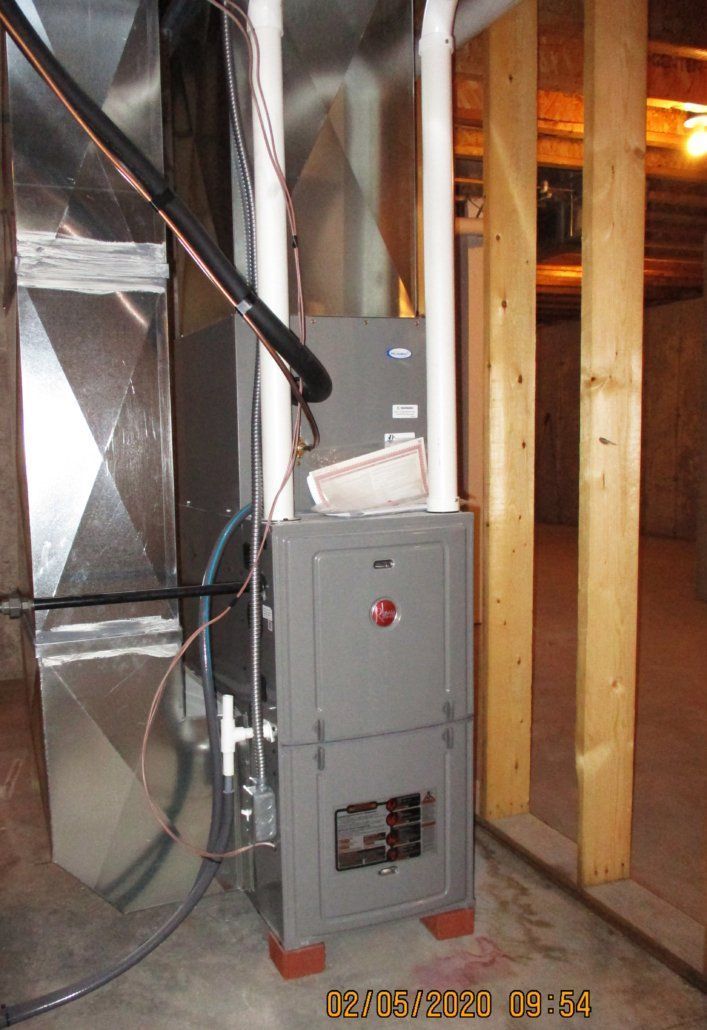 Gray furnace unit in a basement with exposed wooden beams and metal ductwork.