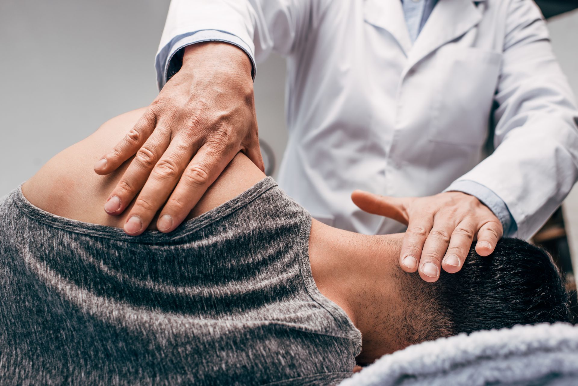 Chiropractor adjusting patient's neck. Hands on shoulders and head; indoors.