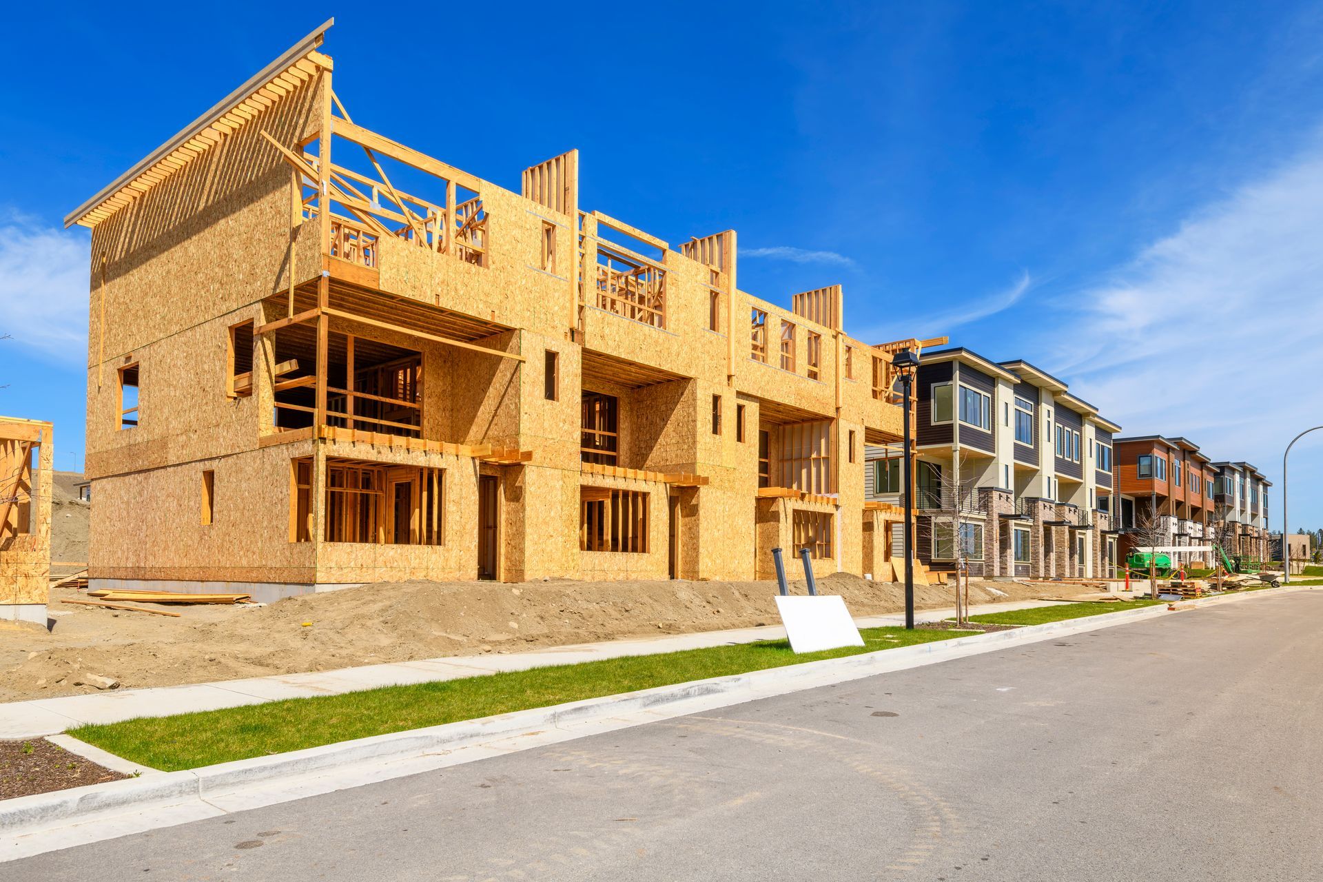 Row of new brick townhomes under construction along a quiet suburban street on a sunny day