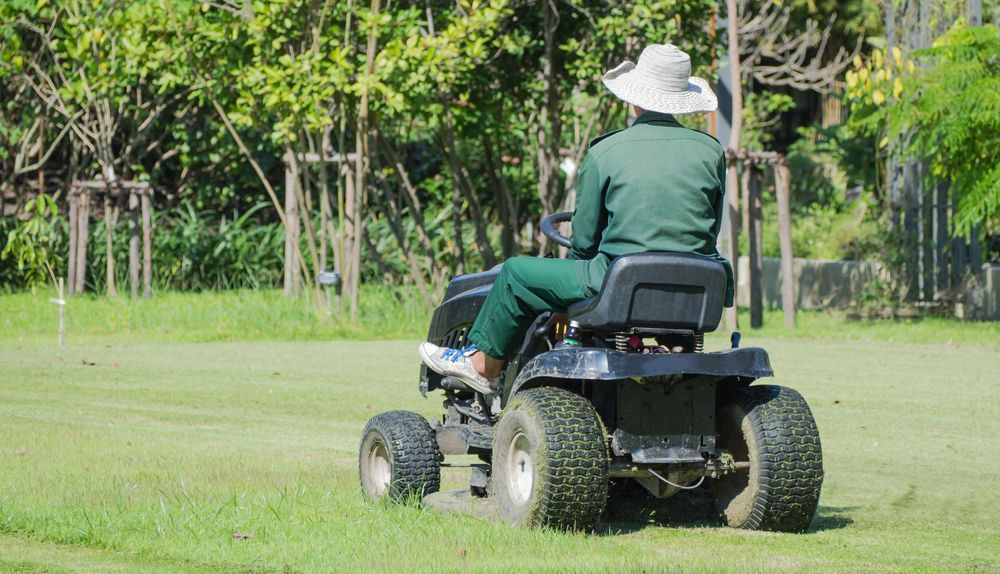 A Man is Fixing a Lawn Mower With Gloves on — Nabiac Mower & Tractor Repairs in Taree, NSW