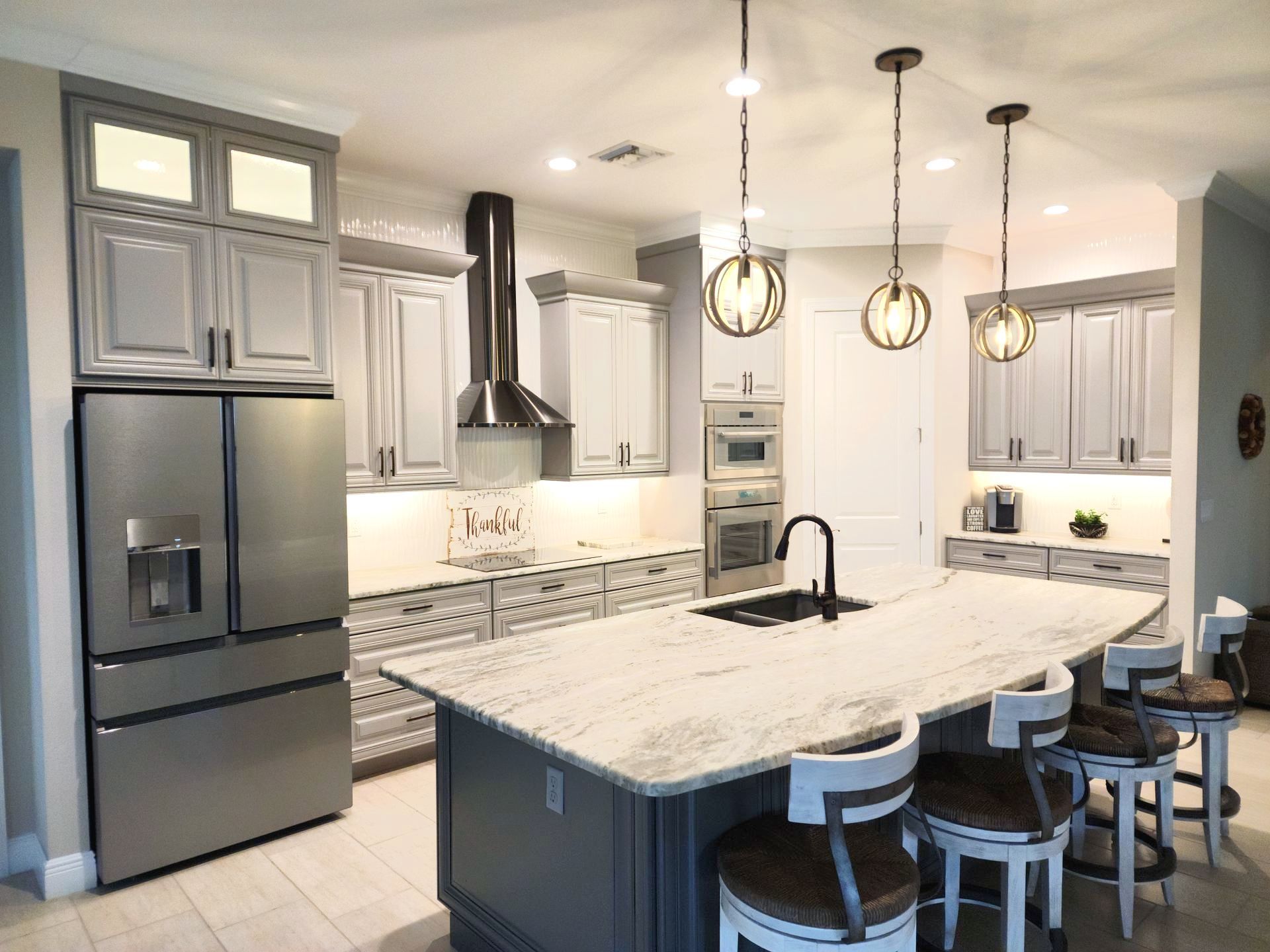 Modern kitchen with gray cabinets, stainless steel appliances, and an island with bar stools.
