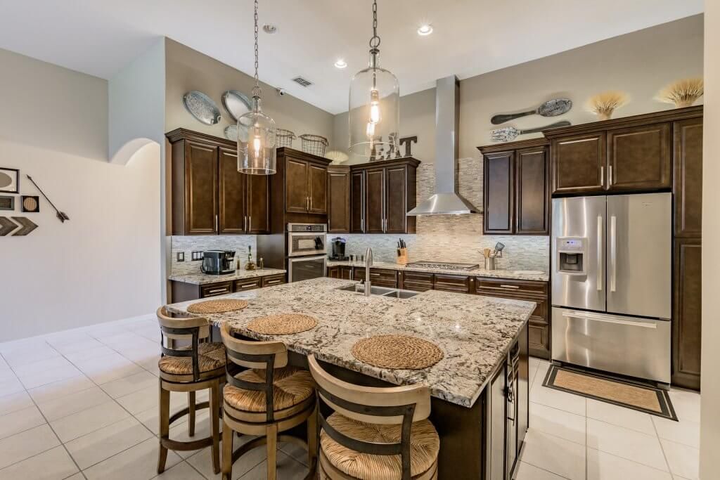 Spacious kitchen with a large island, stainless steel appliances, and dark wood cabinets.