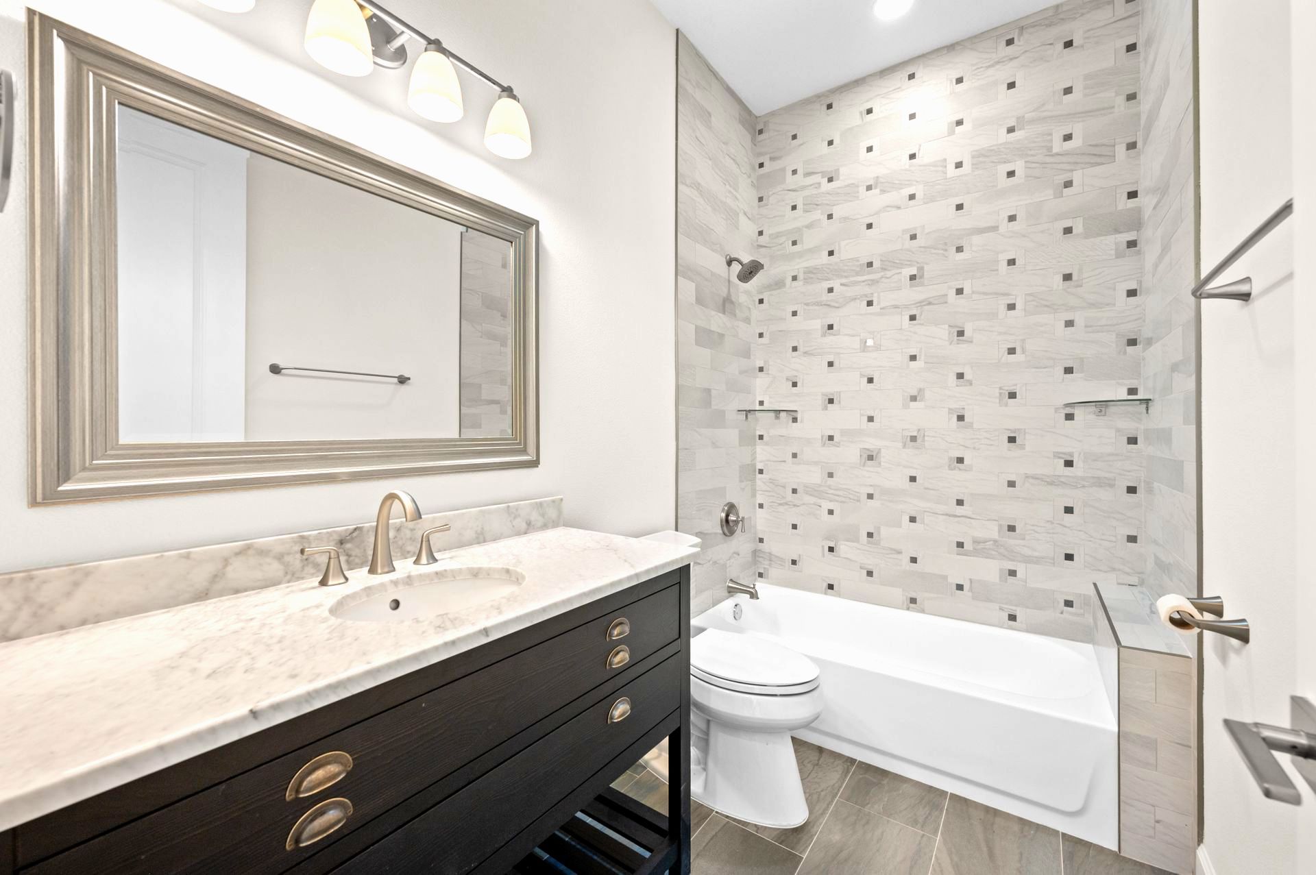 Bathroom remodeling in Sarasota with dark vanity, large mirror, bathtub, and patterned tile wall.