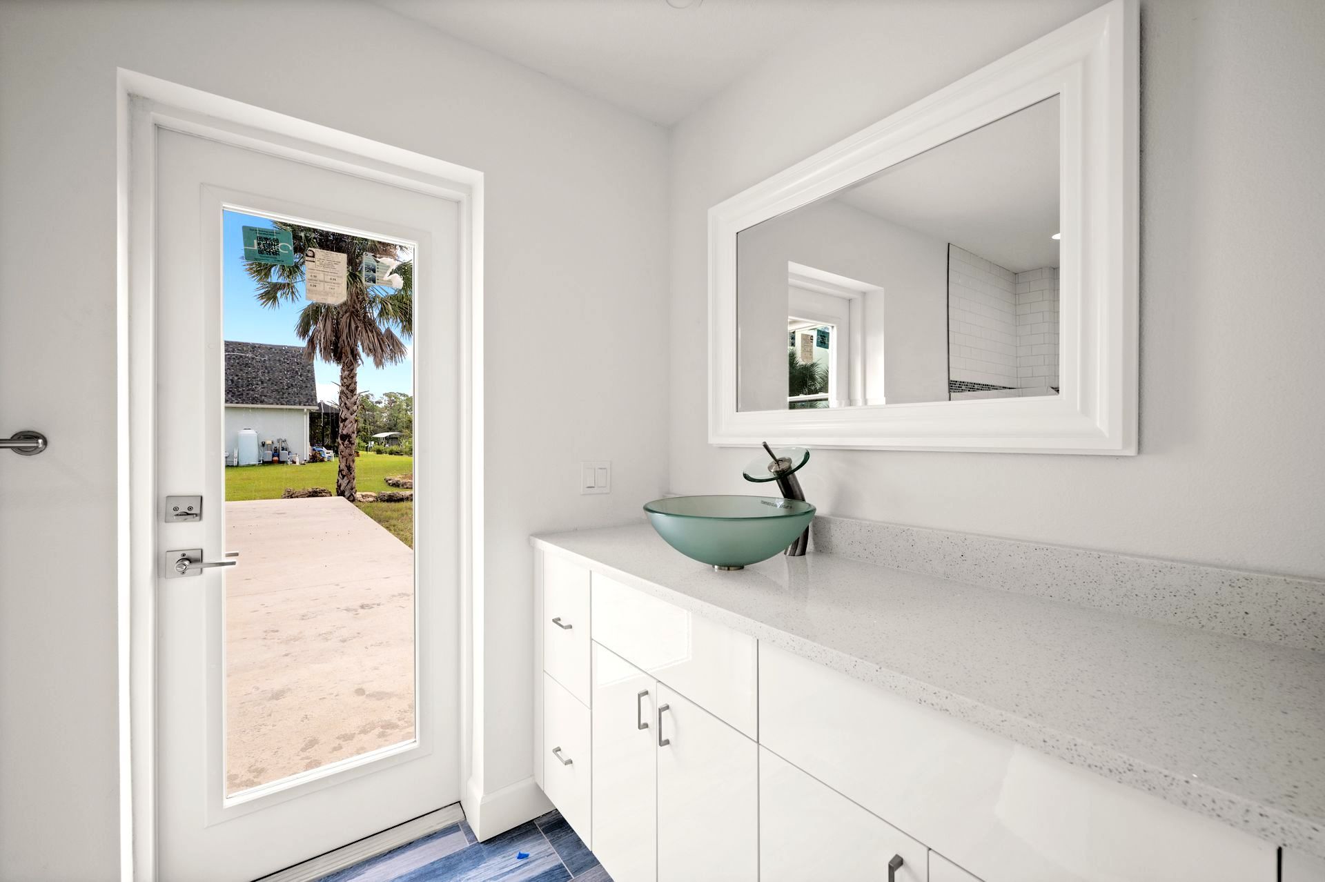 Bath remodeled in Nokomis with a white vanity, glass bowl sink, large mirror, and a door overlooking a yard.