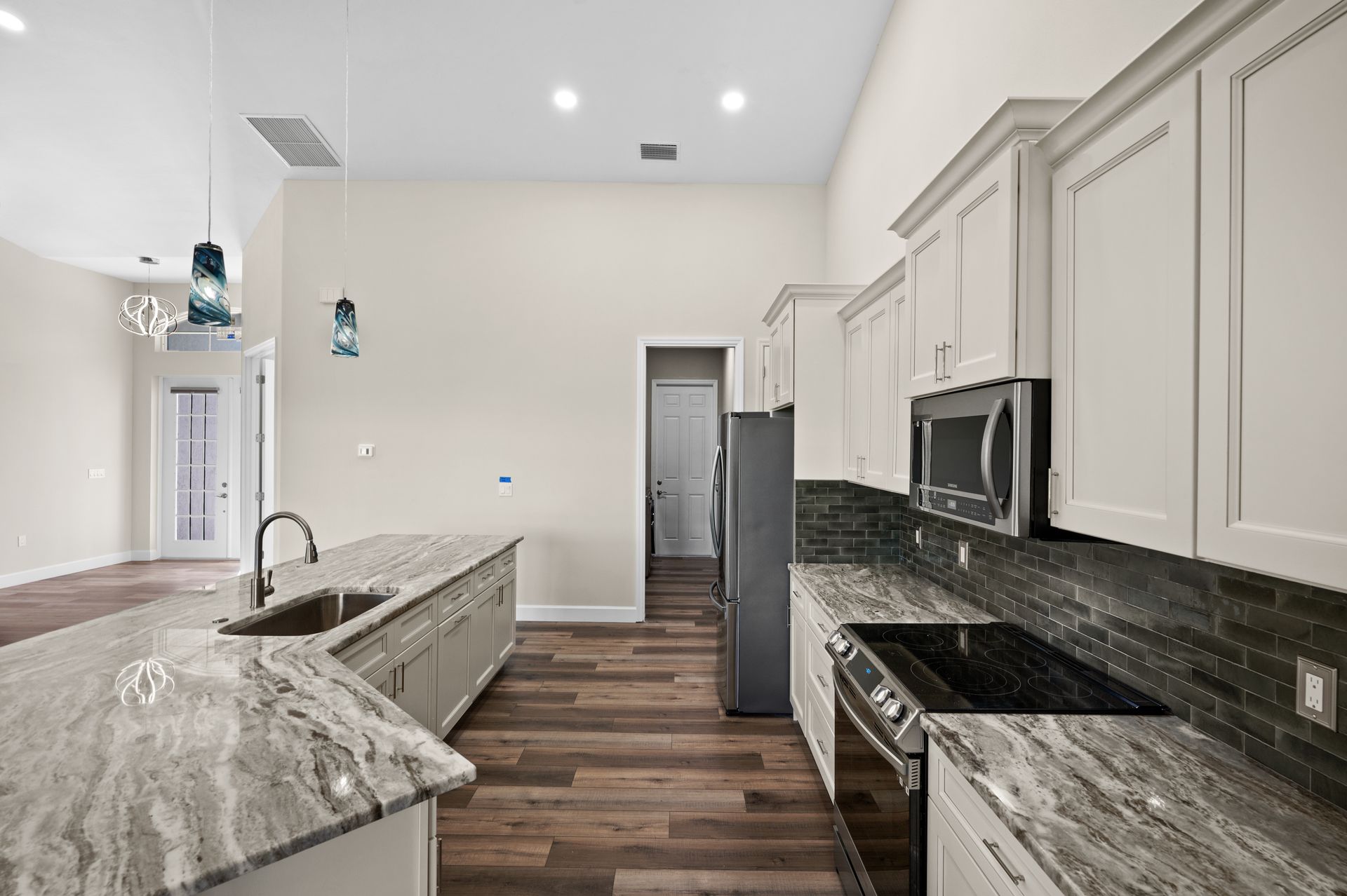 Modern kitchen with granite countertops, stainless steel appliances, and wooden floors.