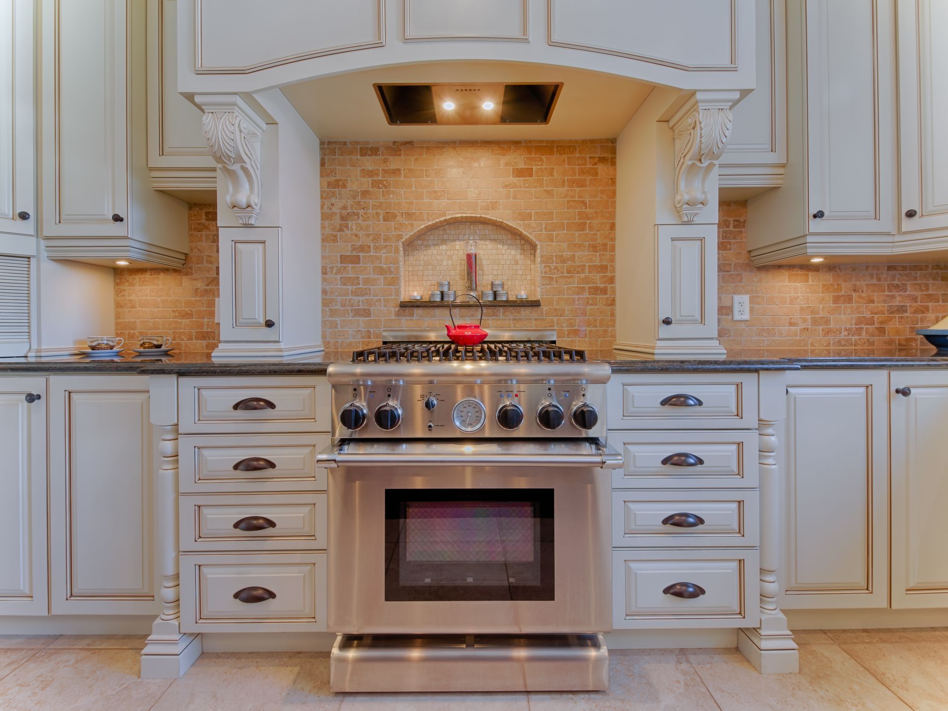 Kitchen with white cabinets, stainless steel range, and brick backsplash.