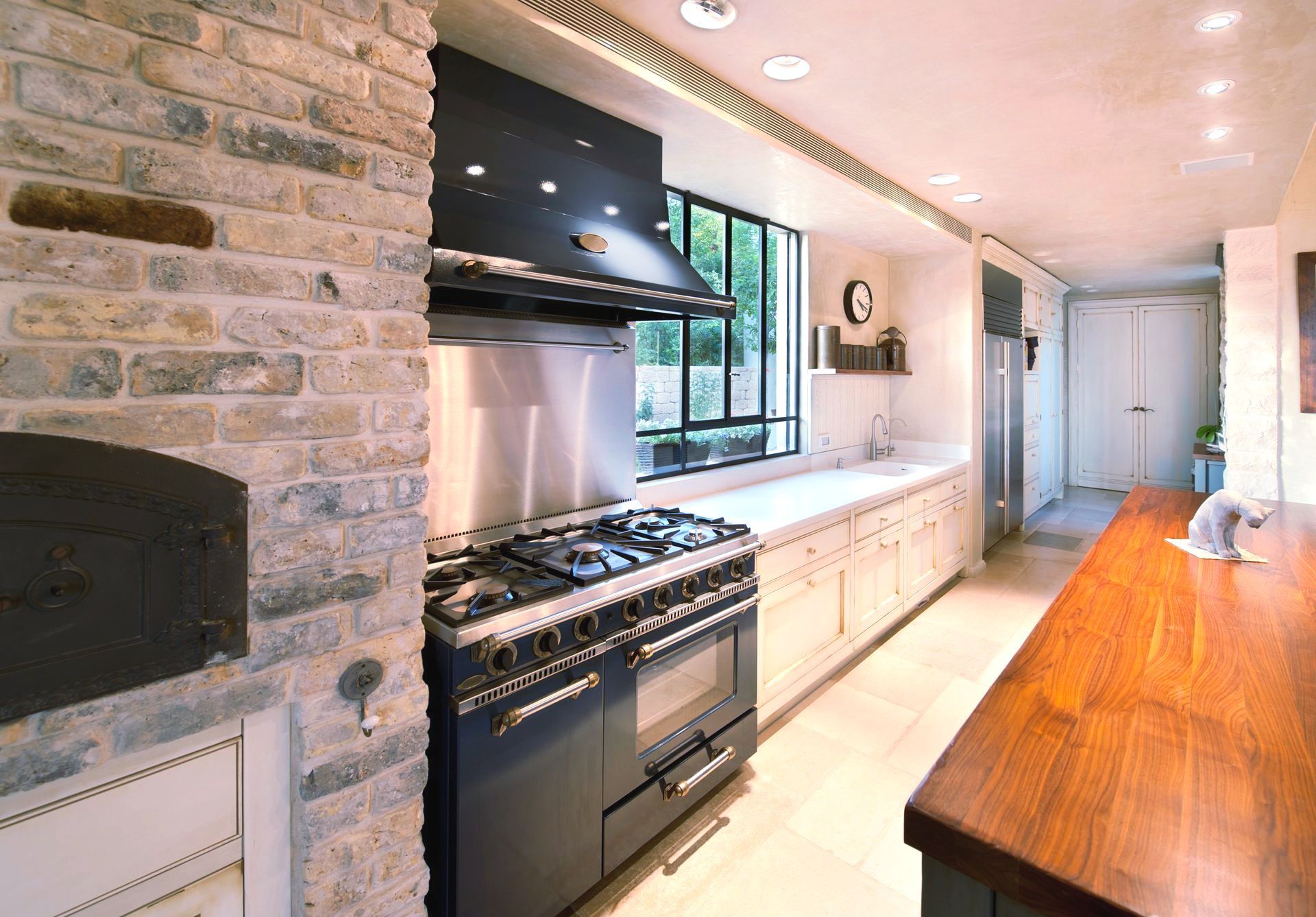 Modern kitchen with brick wall, large oven, long countertop, and window.
