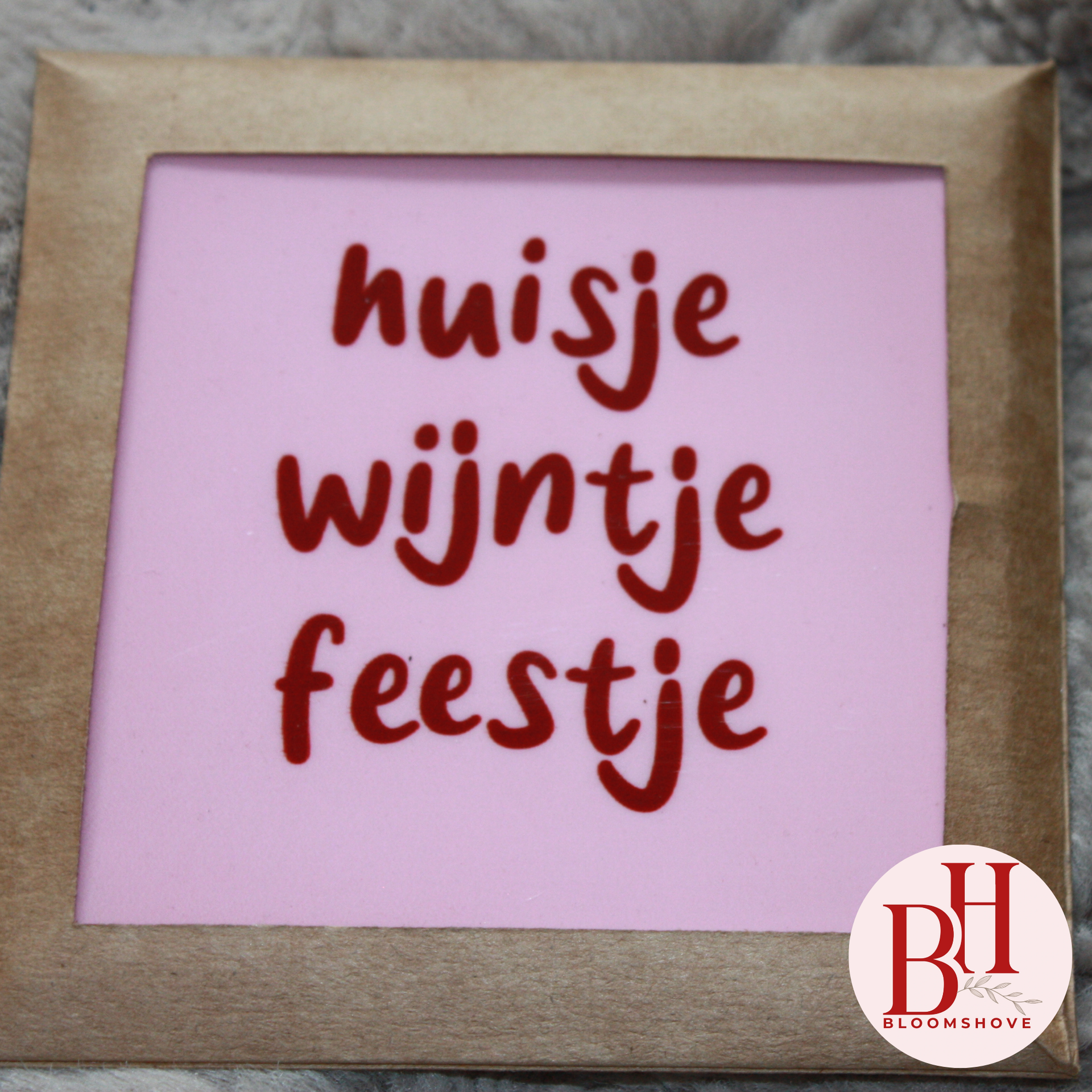 Pink sign with brown handwritten Dutch text “huisje wijntje feestje” in a beige frame.