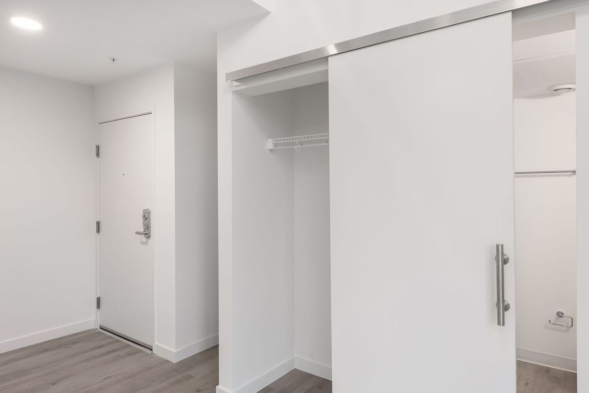 White closet with sliding door in a modern apartment. Includes a door and wooden floors.