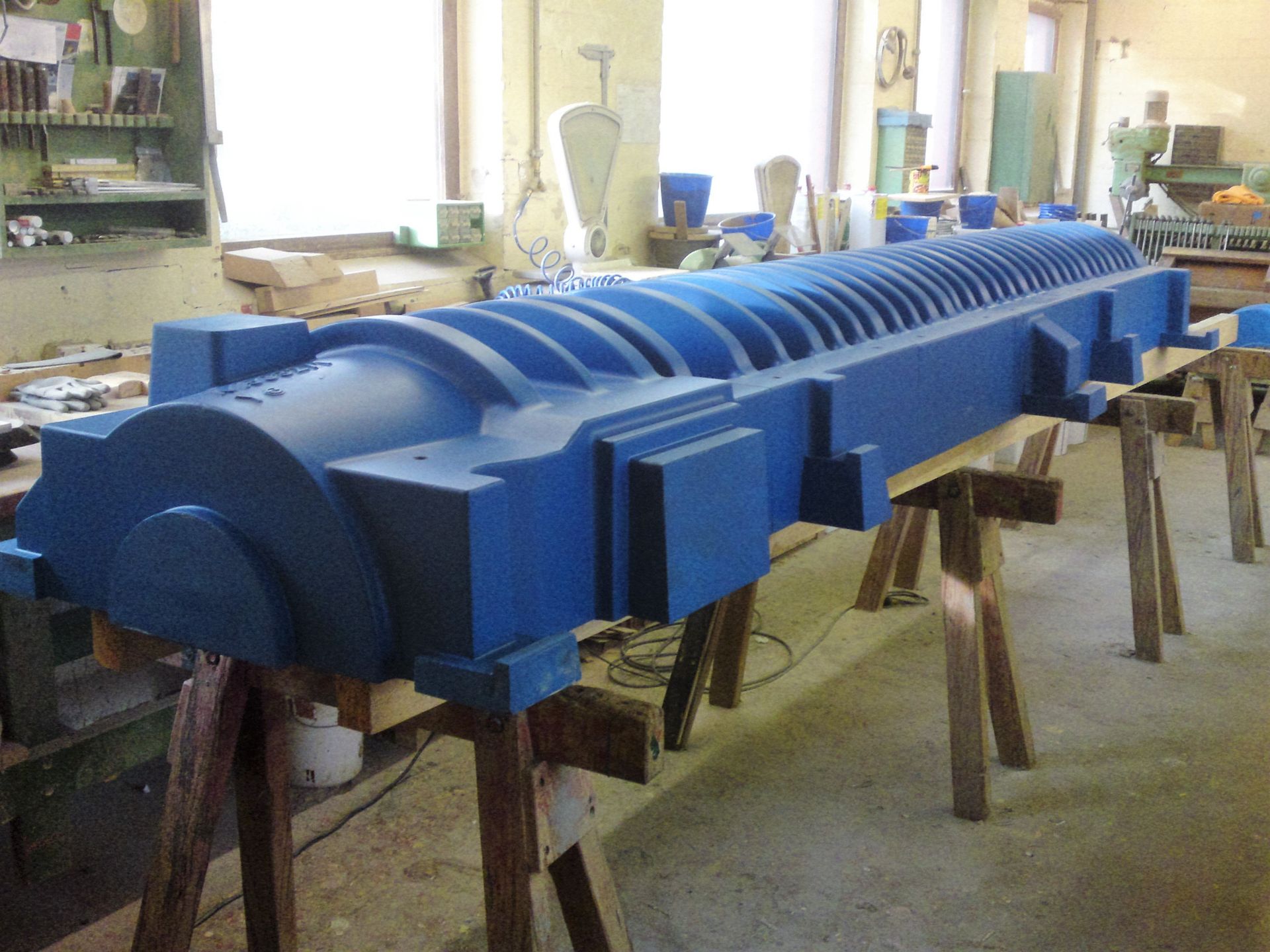 Ein großes blaues Objekt sitzt auf Holzböcken in einem Raum