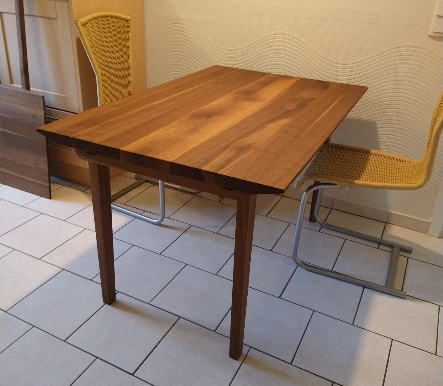 Ein Holztisch mit einem Korbstuhl daneben