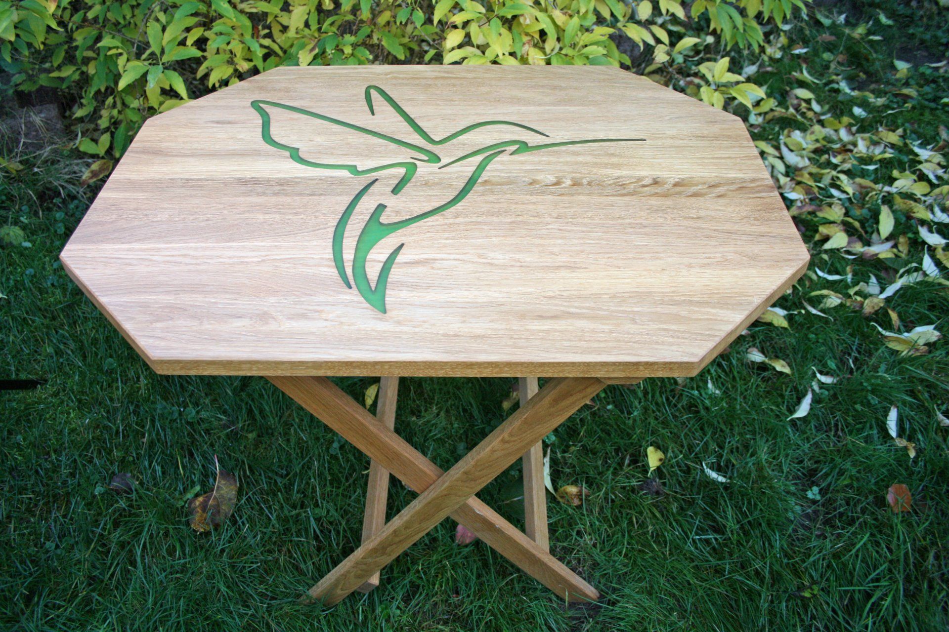 Ein Holztisch mit einem grünen Kolibri darauf
