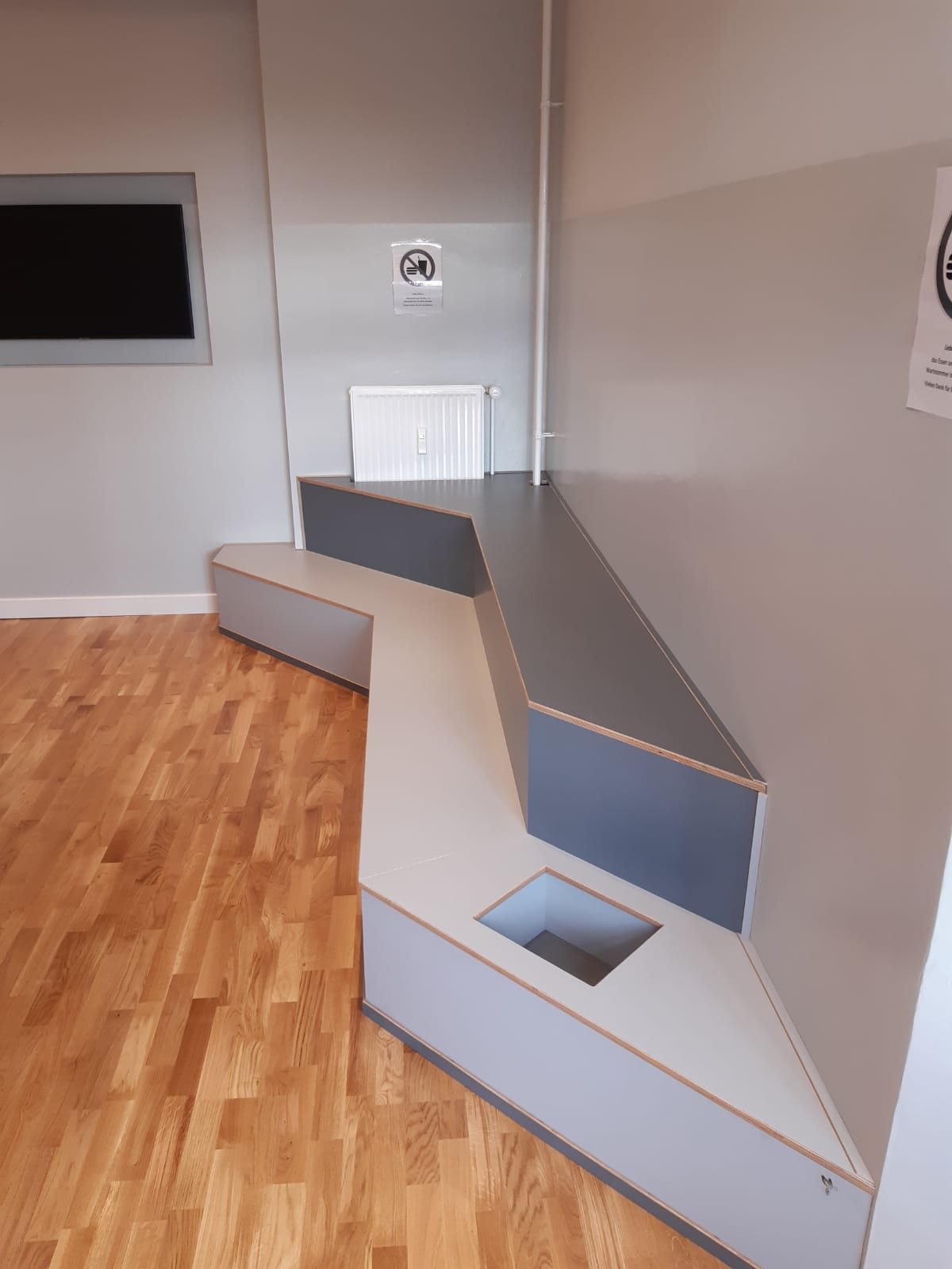 In der Mitte des Raumes steht eine Bank, an der Wand hängt ein Fernseher.