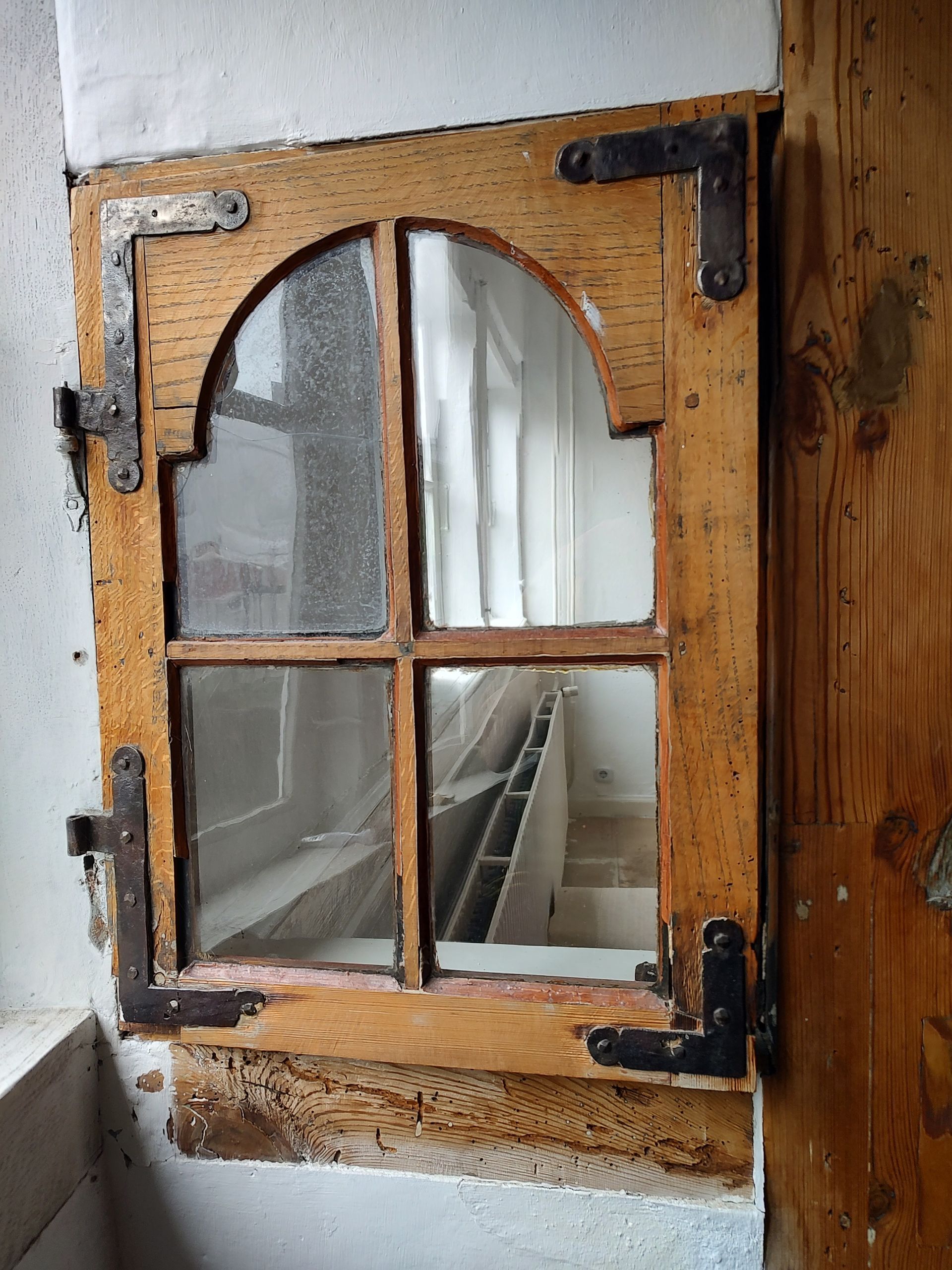 Ein Holzfenster mit einem Metallscharnier an einer weißen Wand
