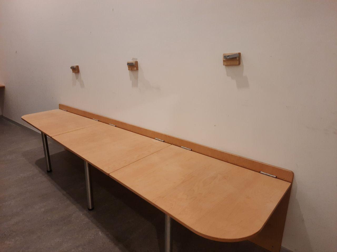 Ein langer Holztisch in einem Raum mit einer weißen Wand