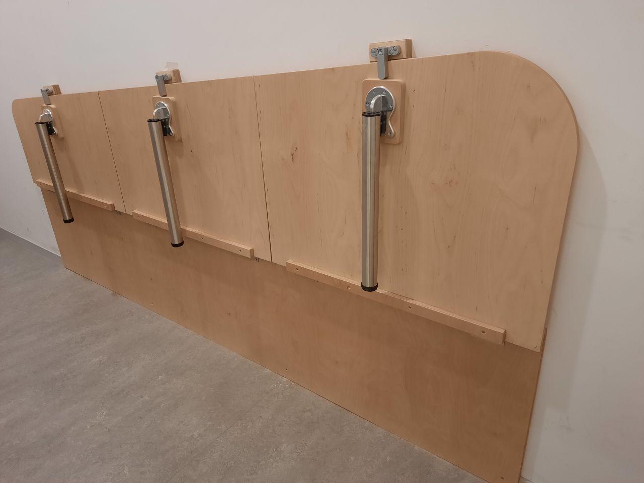 Ein an der Wand montierter Holztisch mit daran befestigten Metallgriffen.