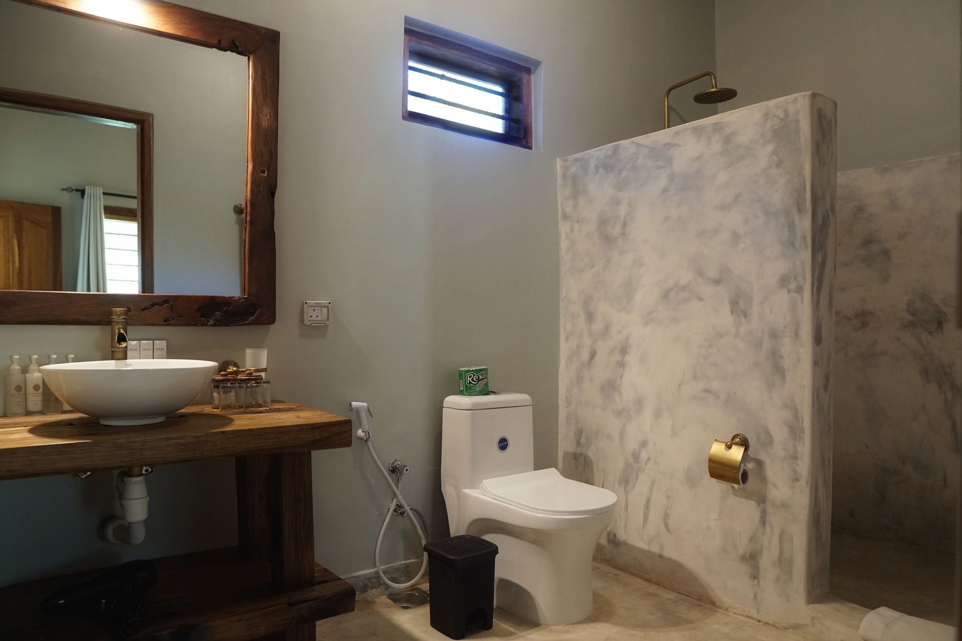 Bathroom with sink, mirror, toilet, shower, and marble-patterned stall walls.