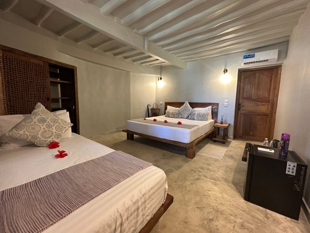Cozy bedroom with two beds, wooden furniture, and warm wall lighting