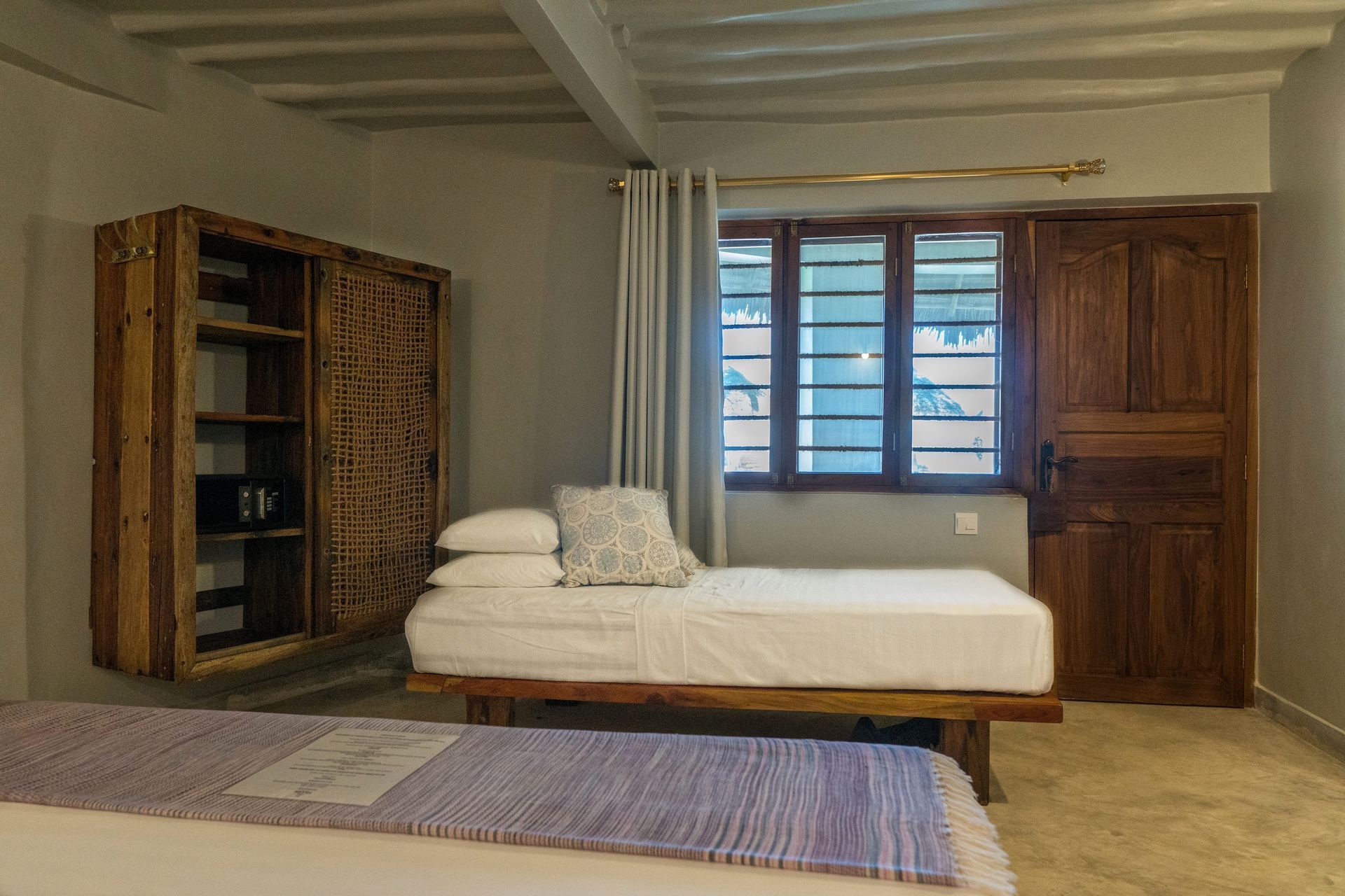 Spare bedroom with a bed, wooden wardrobe, window shutters, and neutral decor