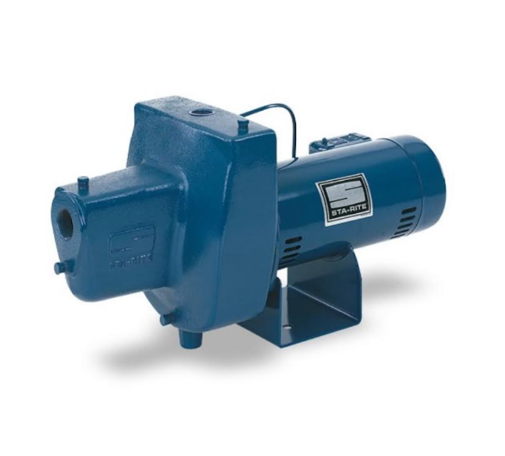 A blue and black water pump is sitting on a concrete wall next to a pool.