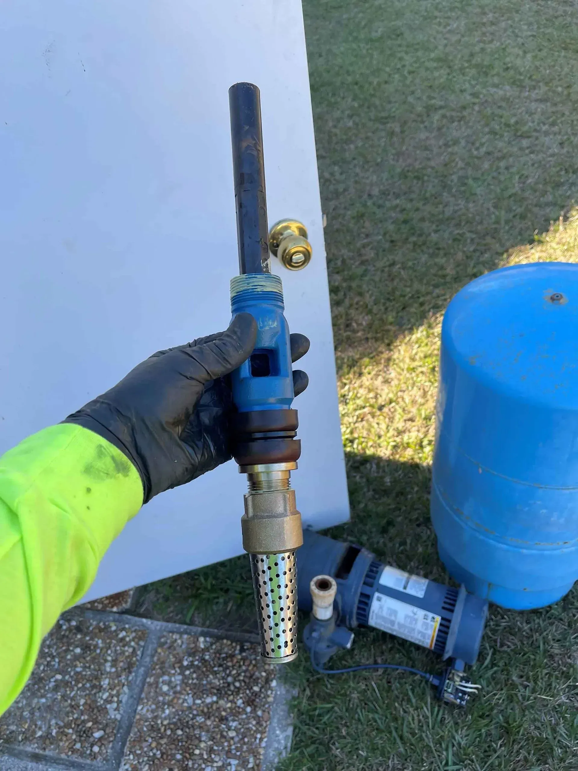 A person is holding a water pump in their hand in front of a door.