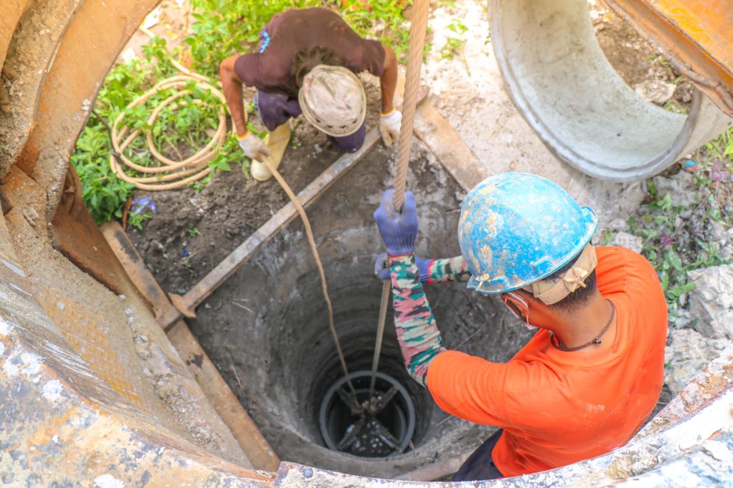A couple of men are working on a well.