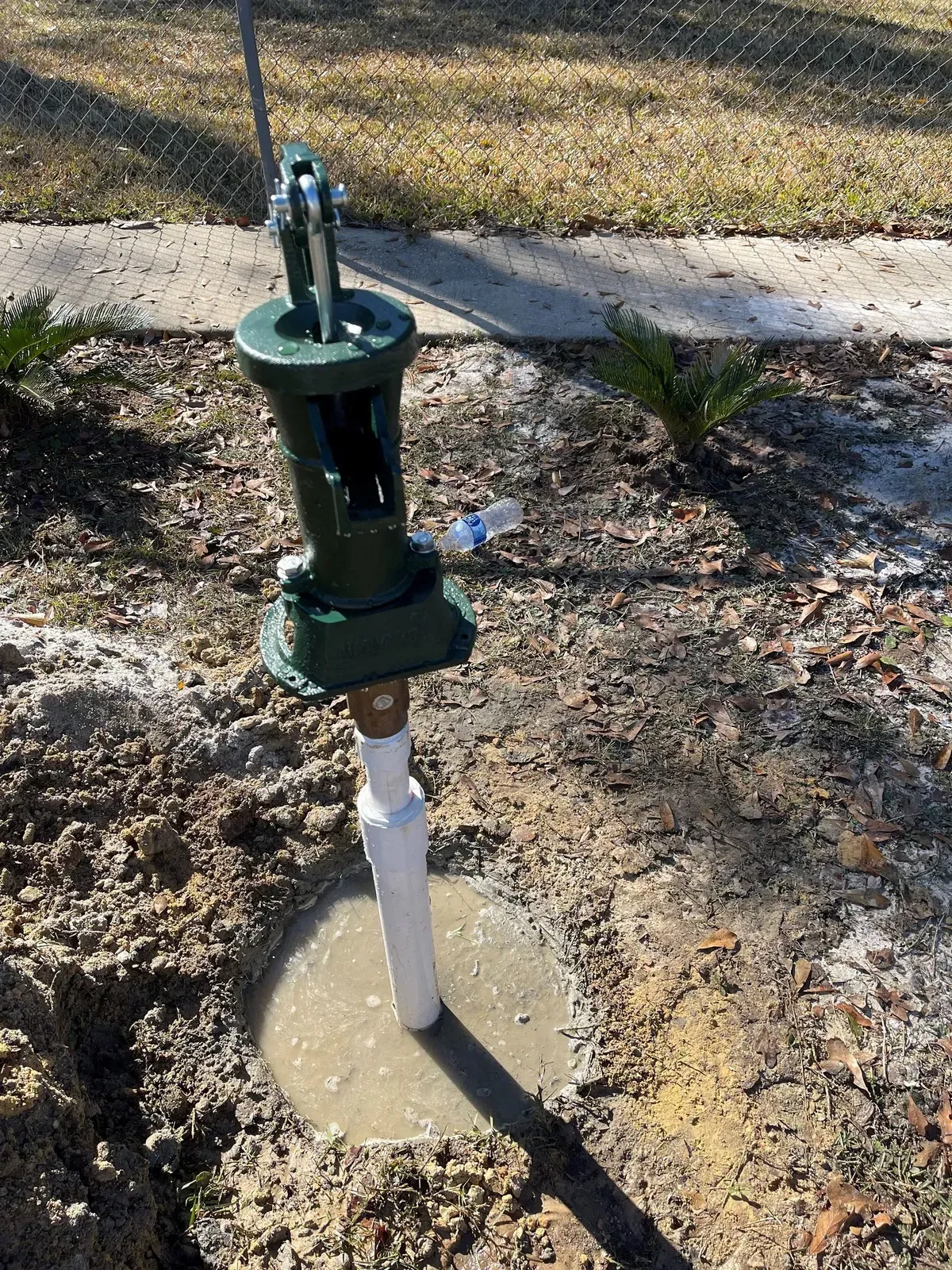 A water pump is sitting on the ground next to a building.