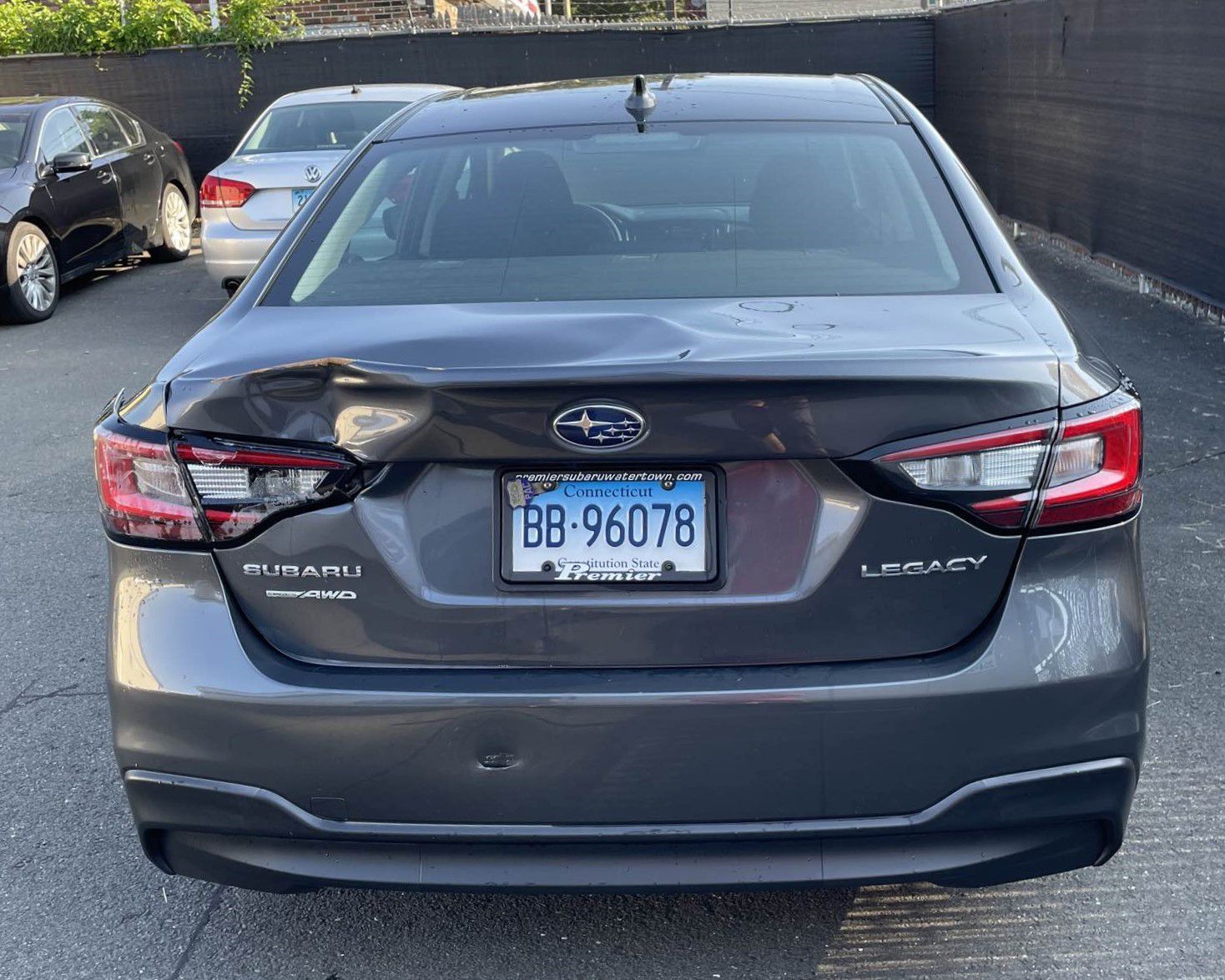 A gray subaru legacy is parked in a parking lot.