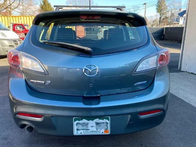 A mazda 3 hatchback is parked in a parking lot.