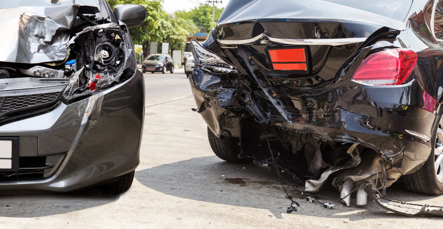Two cars with collision damage stopped along the side of a road after an accident