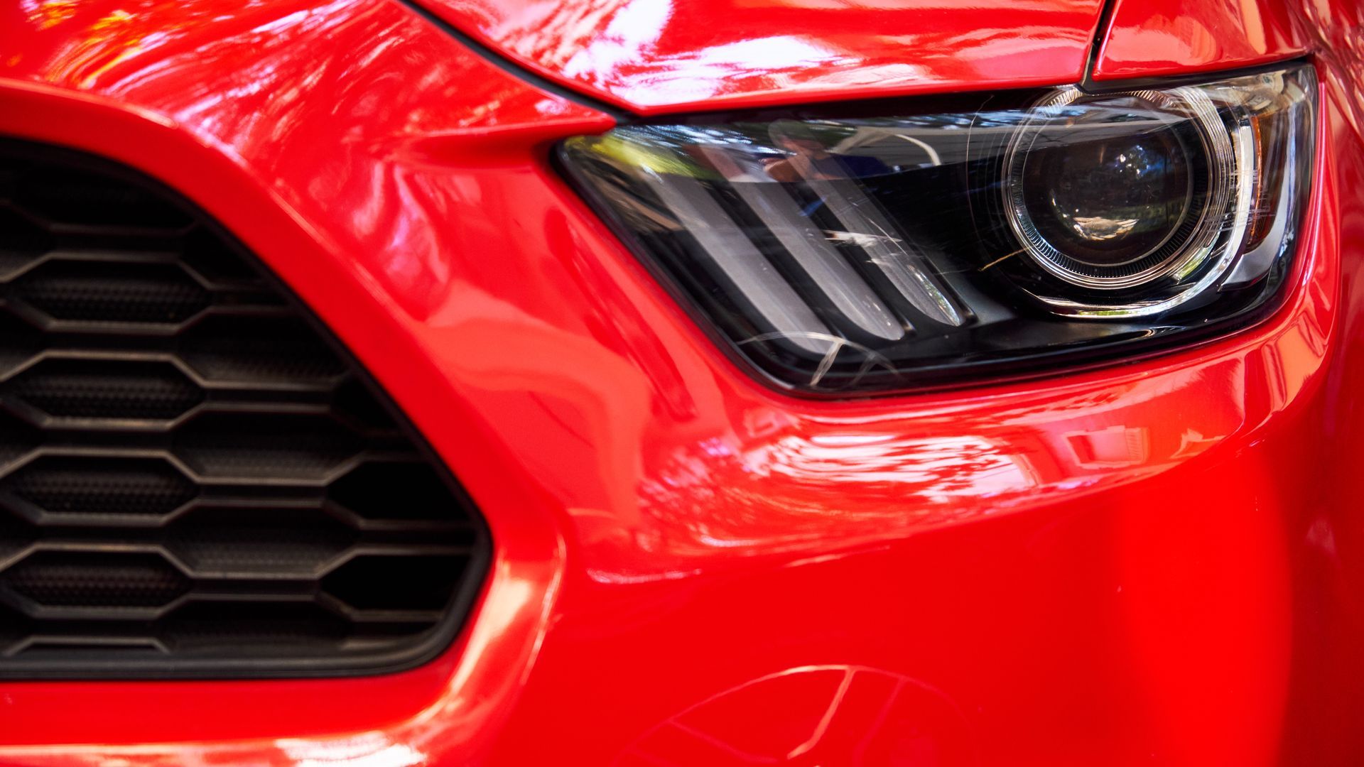 Close up of a red car's headlight and front grille after collision repair