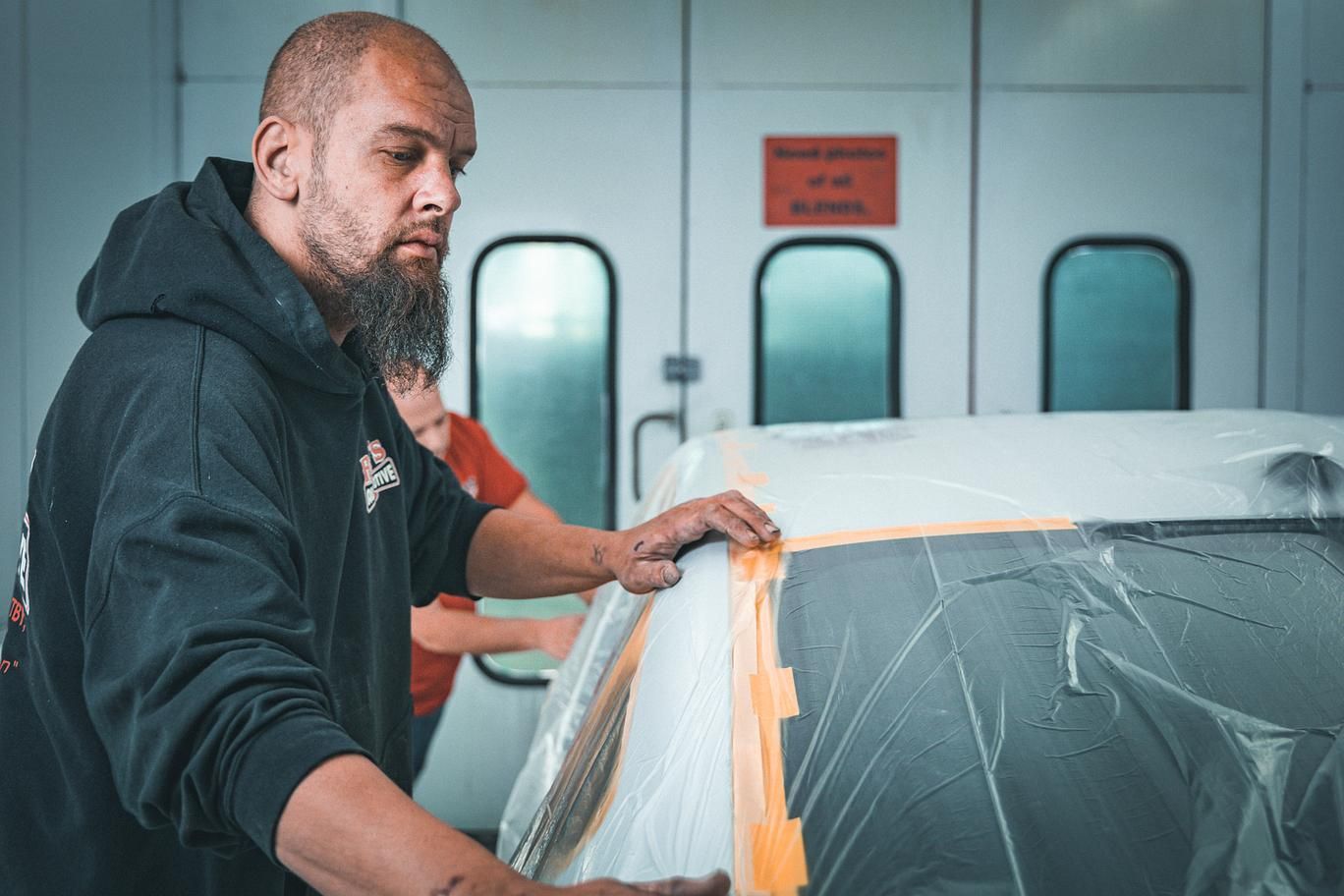 Person taping off a car in a paint booth