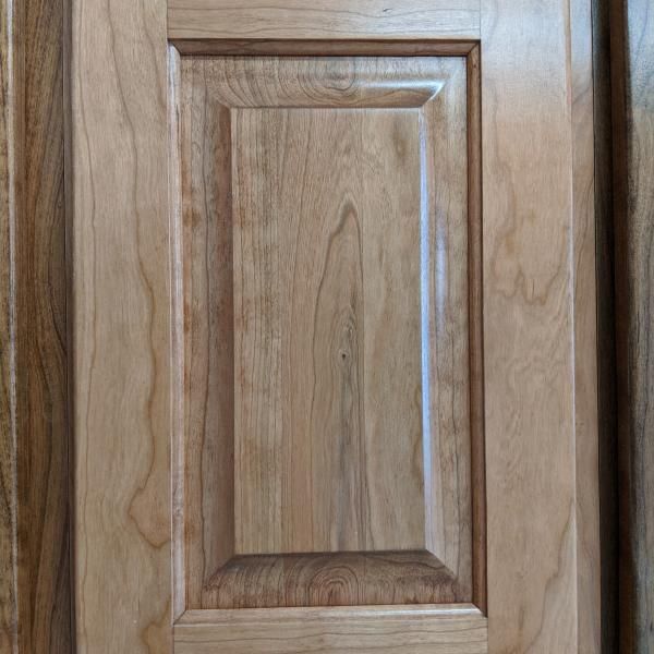 Wooden cabinet door with a raised center panel and natural wood grain finish